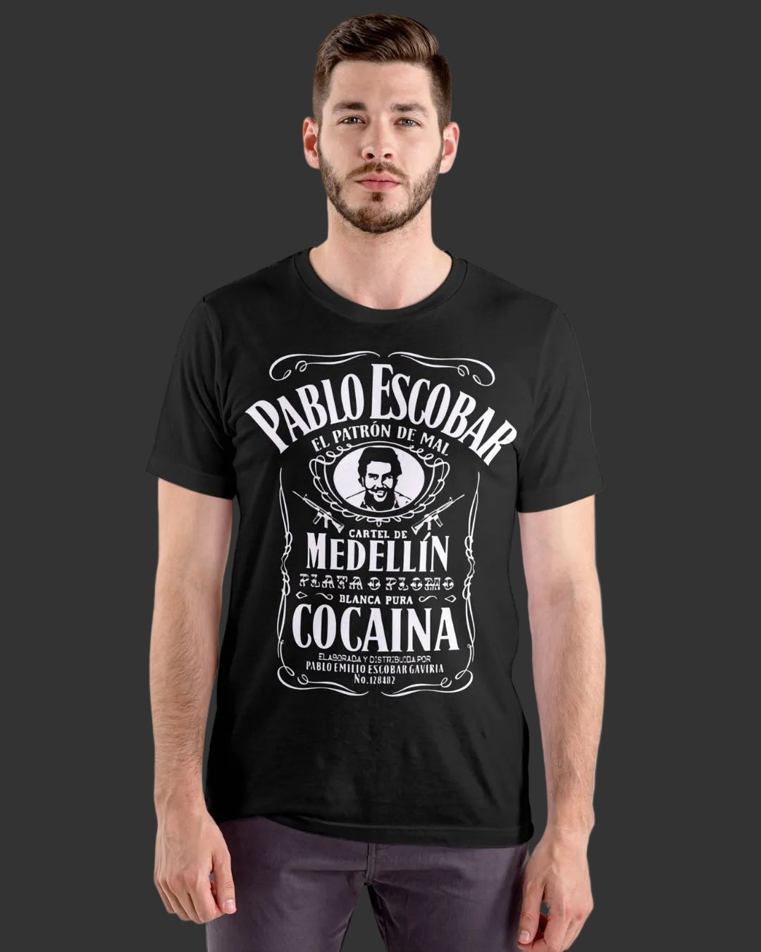 A man wearing a black short-sleeve t-shirt with a white graphic print on the front. The graphic features a skull and crossbones and stylized text reading 'PABLO ESCOBAR', 'CAPITAN DE MEDELLIN', and 'COCAINA'.