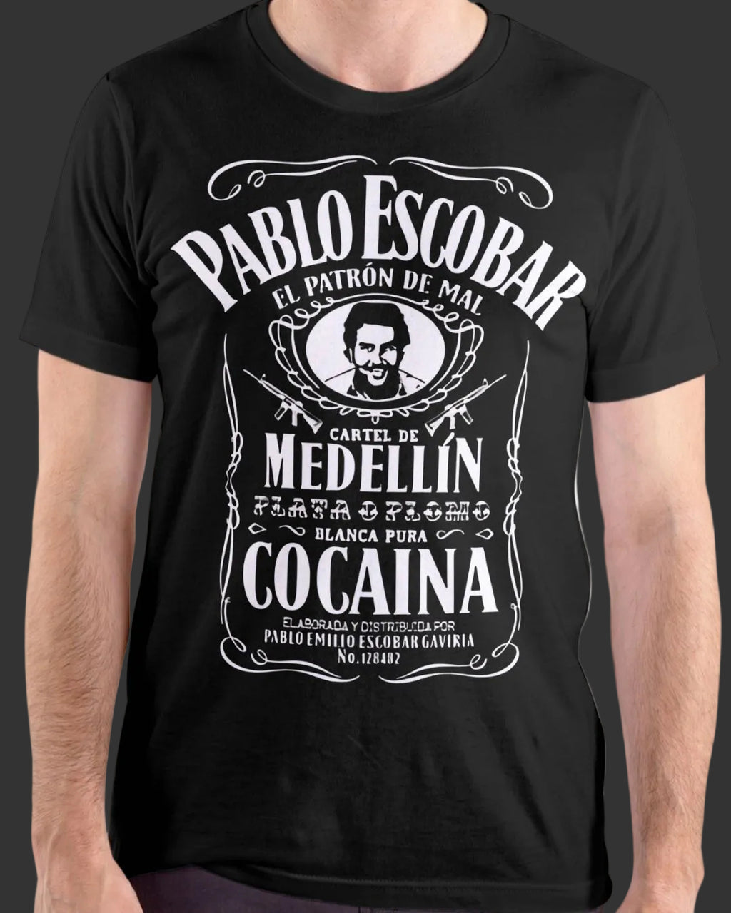 A man wearing a black short-sleeve t-shirt with a large white graphic print styled like a vintage Pablo Escobar Medellin Cocaina label.